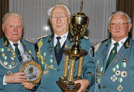 Mit einem Wanderpokal zeichneten Georg Hörmeyer (links) und Stefan Lünswilken (rechts) ihren Vereinskameraden Bernhard Herzog zum „Schützen des Jahres“ aus.